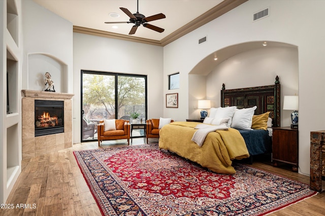 bedroom featuring a tile fireplace, light hardwood / wood-style flooring, access to outside, and ornamental molding