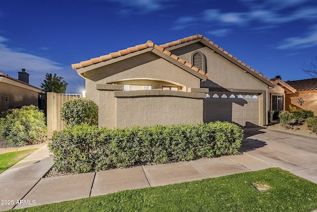 view of front facade with a garage, driveway, a tiled roof, fence, and stucco siding