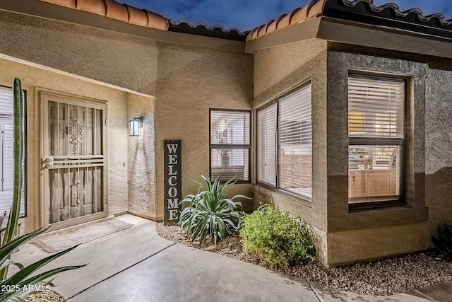 doorway to property with a tile roof and stucco siding