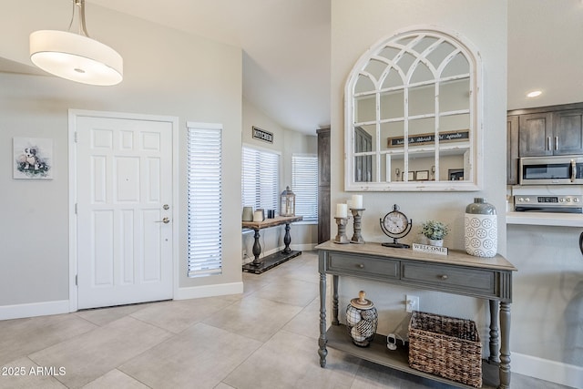 entrance foyer featuring lofted ceiling, light tile patterned flooring, and baseboards