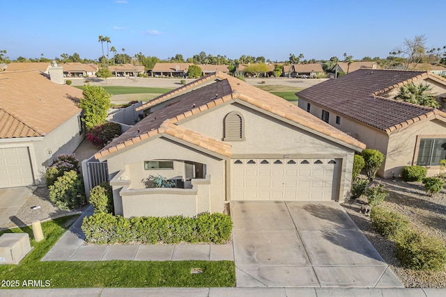 mediterranean / spanish home with a garage, driveway, a tile roof, a residential view, and stucco siding