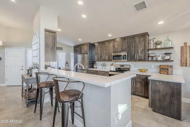 kitchen with a breakfast bar, light tile patterned floors, visible vents, appliances with stainless steel finishes, and dark brown cabinets