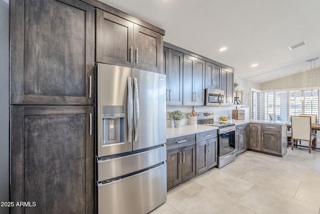 kitchen with light tile patterned floors, lofted ceiling, appliances with stainless steel finishes, a peninsula, and light countertops