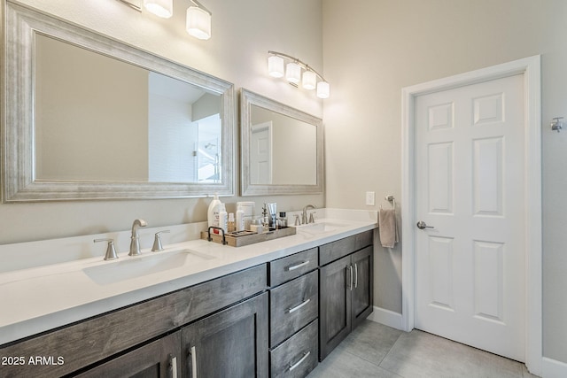 full bathroom with tile patterned flooring, a sink, baseboards, and double vanity