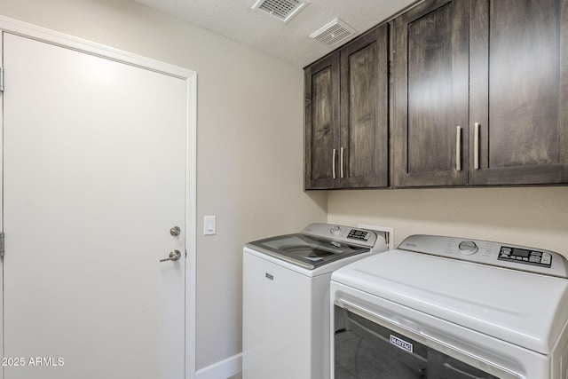 clothes washing area featuring cabinet space, washing machine and dryer, visible vents, and a textured ceiling