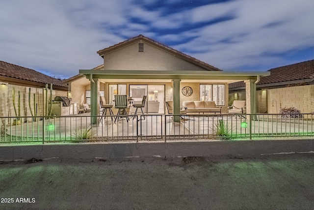 view of front facade with fence, a patio, and stucco siding