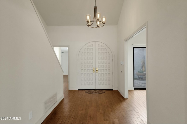 foyer featuring french doors, hardwood / wood-style flooring, and a notable chandelier