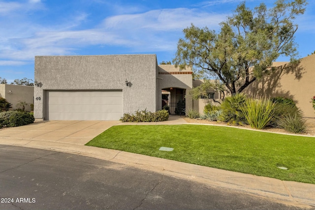 pueblo revival-style home with a front yard and a garage