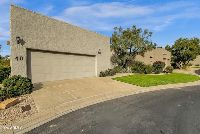 pueblo-style home featuring a garage and a front lawn