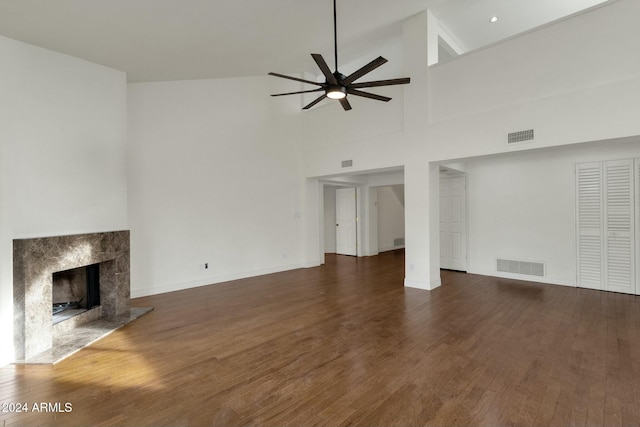 unfurnished living room featuring a premium fireplace, high vaulted ceiling, dark hardwood / wood-style floors, and ceiling fan