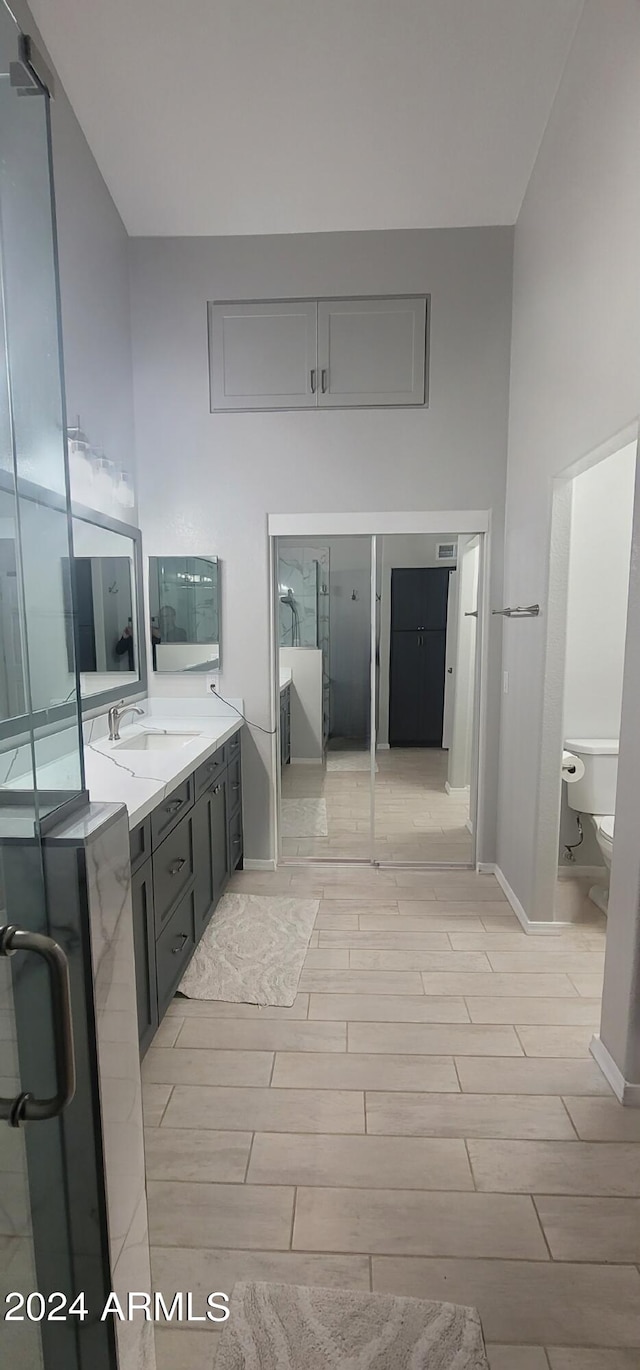 bathroom with vanity, toilet, wood-type flooring, and a towering ceiling