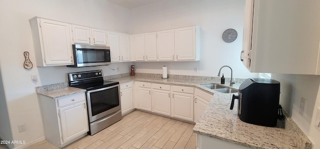 kitchen featuring light stone counters, appliances with stainless steel finishes, white cabinetry, light wood-type flooring, and sink