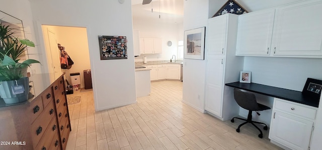 office space featuring a towering ceiling, light hardwood / wood-style flooring, built in desk, and sink