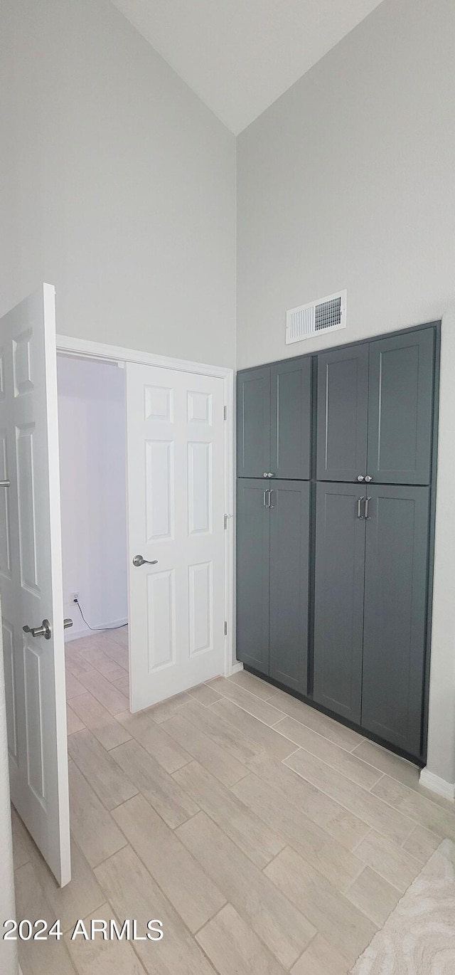 unfurnished bedroom with a closet, high vaulted ceiling, and light wood-type flooring