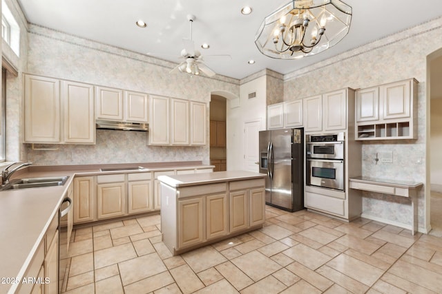 kitchen with appliances with stainless steel finishes, a center island, a sink, light countertops, and under cabinet range hood