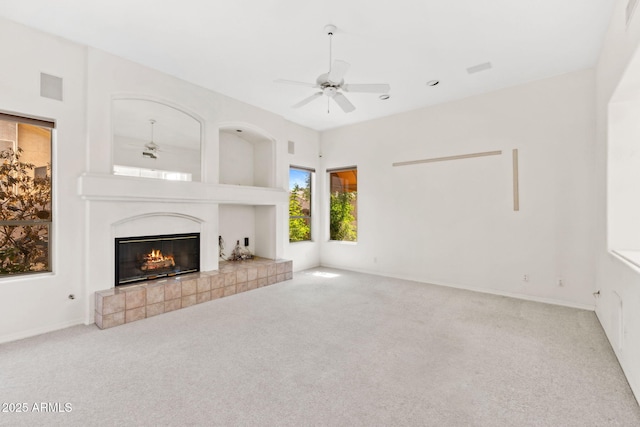 unfurnished living room with baseboards, ceiling fan, a fireplace, and carpet flooring