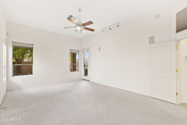 carpeted spare room featuring a healthy amount of sunlight, track lighting, ceiling fan, and visible vents