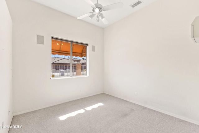 carpeted spare room with visible vents, baseboards, and ceiling fan