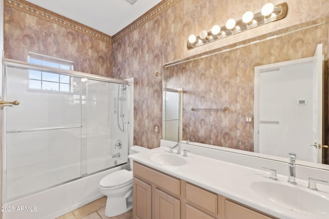 bathroom featuring double vanity, a sink, bath / shower combo with glass door, and toilet