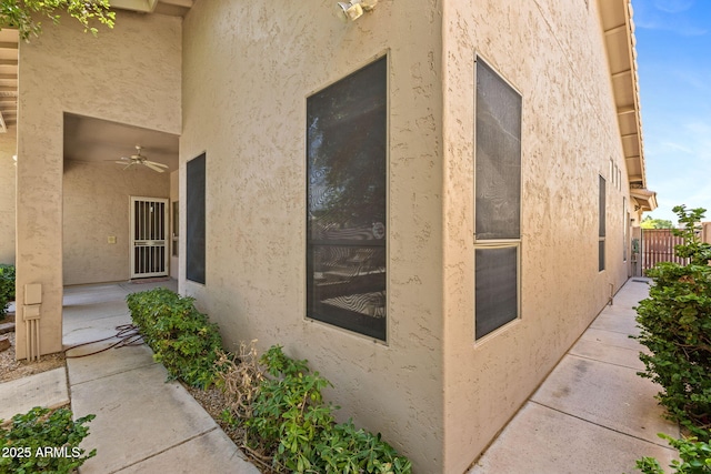 view of home's exterior with ceiling fan, fence, and stucco siding