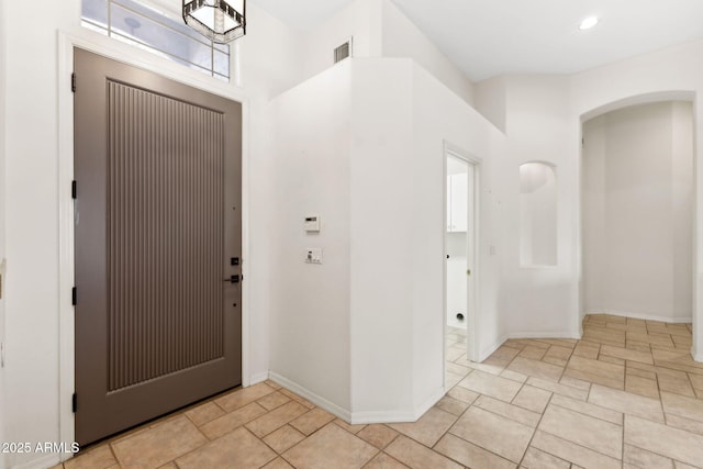 entrance foyer featuring arched walkways, baseboards, recessed lighting, and visible vents