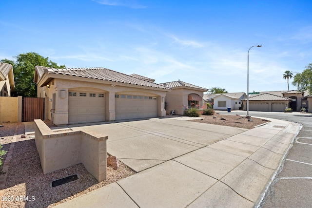 view of front of home featuring a tiled roof, a garage, fence, concrete driveway, and stucco siding