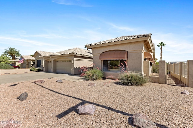 mediterranean / spanish-style house featuring fence, concrete driveway, stucco siding, and an attached garage