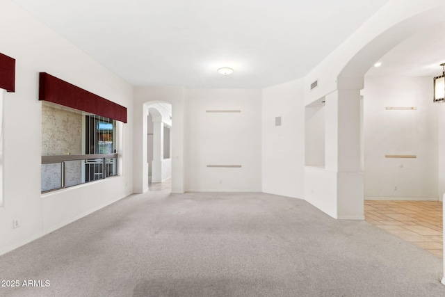 spare room featuring arched walkways, carpet, and visible vents