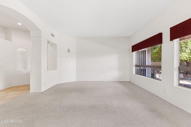 carpeted spare room with visible vents, arched walkways, baseboards, and recessed lighting