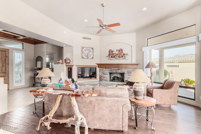 living room featuring a stone fireplace, a healthy amount of sunlight, and hardwood / wood-style floors