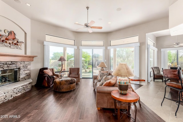 living room with ceiling fan, a healthy amount of sunlight, hardwood / wood-style floors, and a fireplace