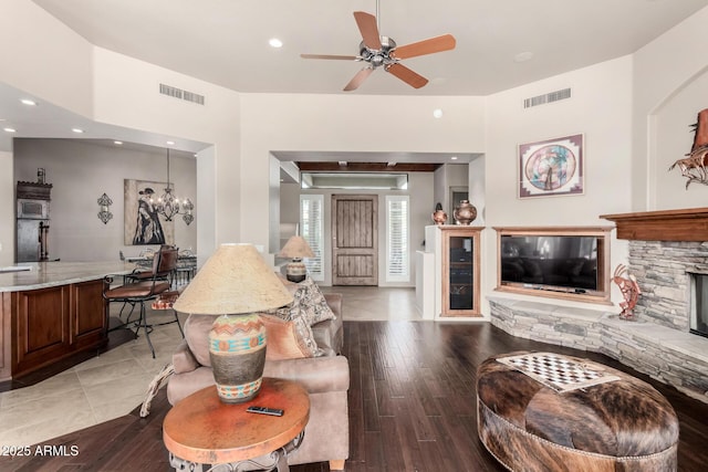 living room featuring ceiling fan with notable chandelier, a fireplace, and light hardwood / wood-style floors