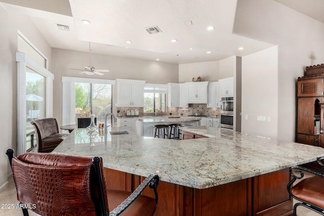 kitchen featuring a large island, sink, light stone counters, and a breakfast bar area