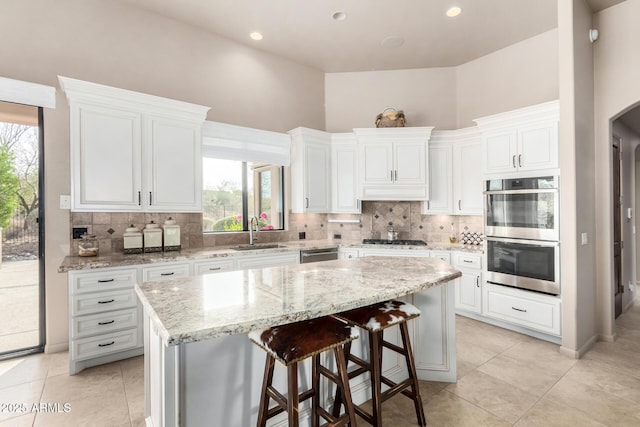 kitchen with a kitchen island, appliances with stainless steel finishes, sink, white cabinets, and a kitchen breakfast bar