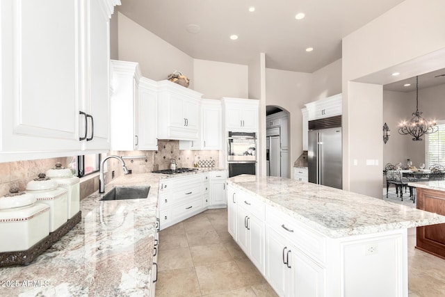 kitchen with white cabinetry, sink, decorative backsplash, a center island, and stainless steel appliances