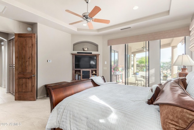 bedroom with a tray ceiling, access to outside, light colored carpet, and ceiling fan