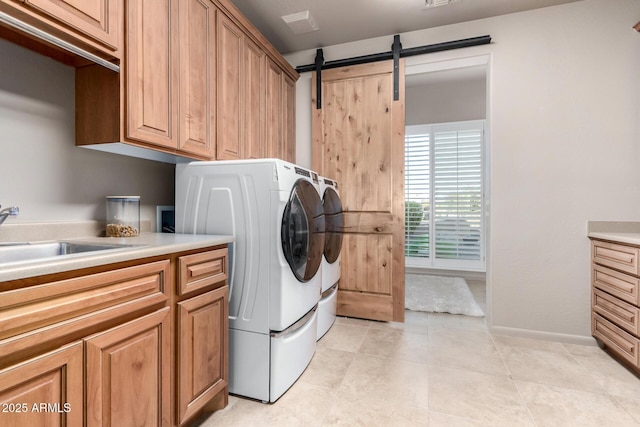 laundry room featuring sink, washing machine and dryer, cabinets, and a barn door