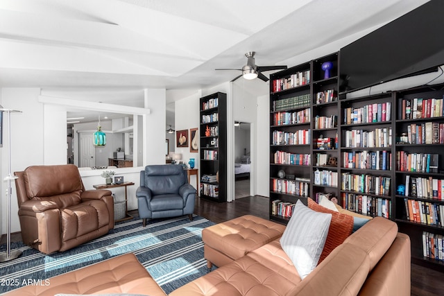 living room with bookshelves, dark wood finished floors, and a ceiling fan