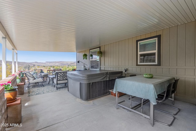 view of patio with a hot tub, a mountain view, and outdoor dining area