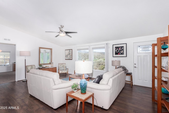 living area featuring a wealth of natural light, lofted ceiling, visible vents, and dark wood-style floors