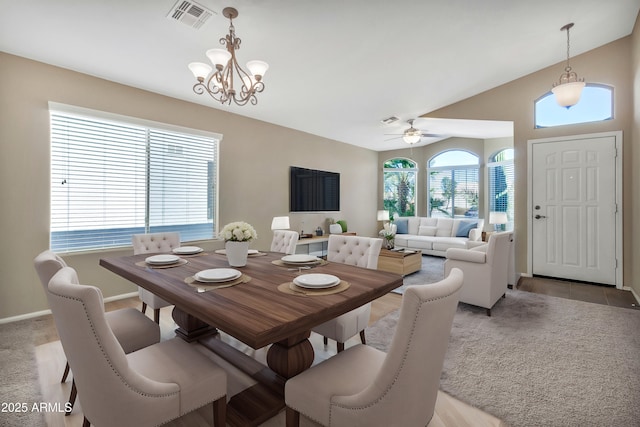 dining space featuring ceiling fan with notable chandelier and lofted ceiling