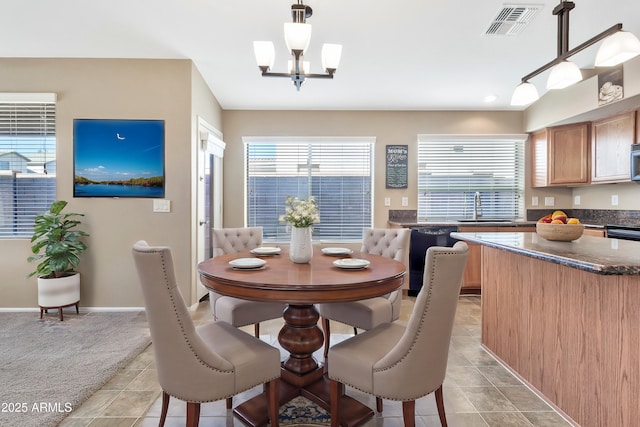 dining area featuring a wealth of natural light, sink, light tile patterned floors, and a chandelier