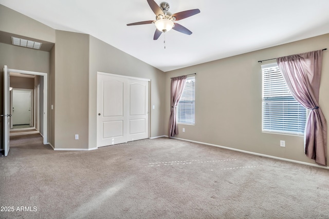 unfurnished bedroom with ceiling fan, lofted ceiling, light carpet, and multiple windows