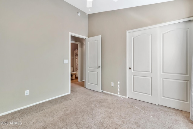 unfurnished bedroom with light carpet, a closet, and lofted ceiling