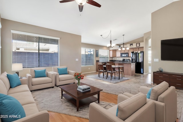 living room with vaulted ceiling, light hardwood / wood-style flooring, and ceiling fan with notable chandelier