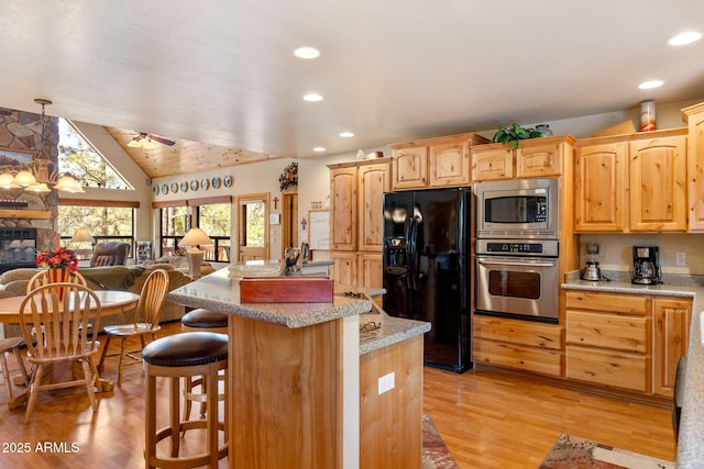 2761 Jaguar Cir, Overgaard, AZ 85933 - kitchen featuring appliances with stainless steel finishes, a kitchen island, light wood-style floors, a kitchen bar, and open floor plan