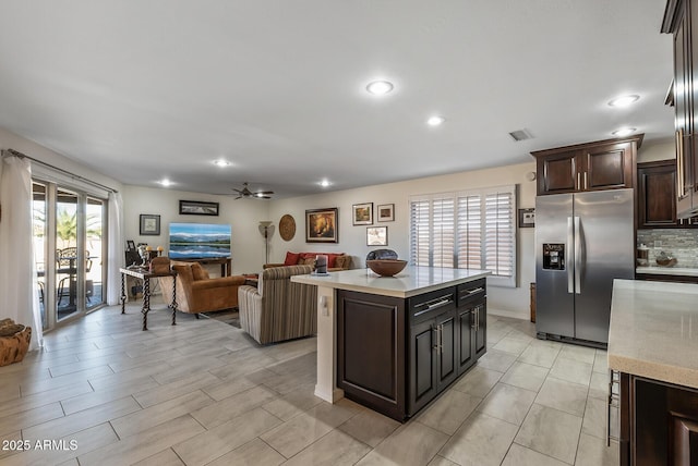 kitchen with ceiling fan, a center island, tasteful backsplash, stainless steel fridge with ice dispenser, and dark brown cabinets