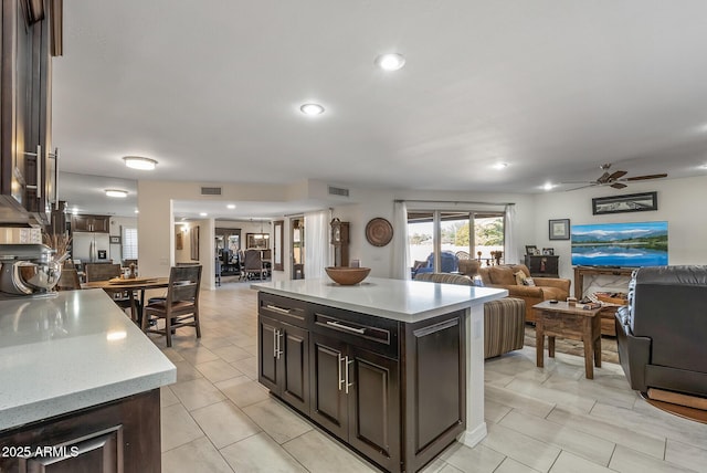 kitchen featuring stainless steel fridge, dark brown cabinetry, a center island, and ceiling fan