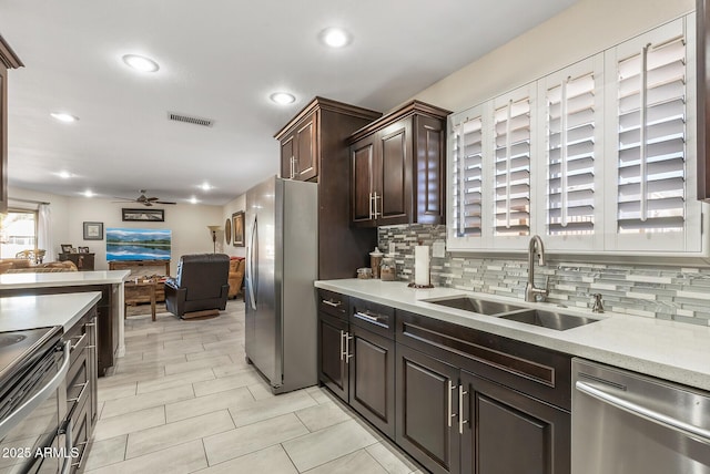 kitchen featuring backsplash, sink, ceiling fan, appliances with stainless steel finishes, and dark brown cabinetry