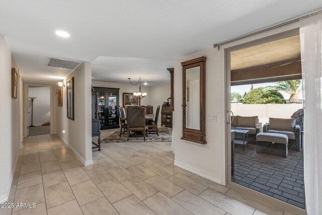 corridor with light tile patterned floors and a notable chandelier